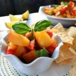 Angled view of grilled peach salsa in a white bowl.
