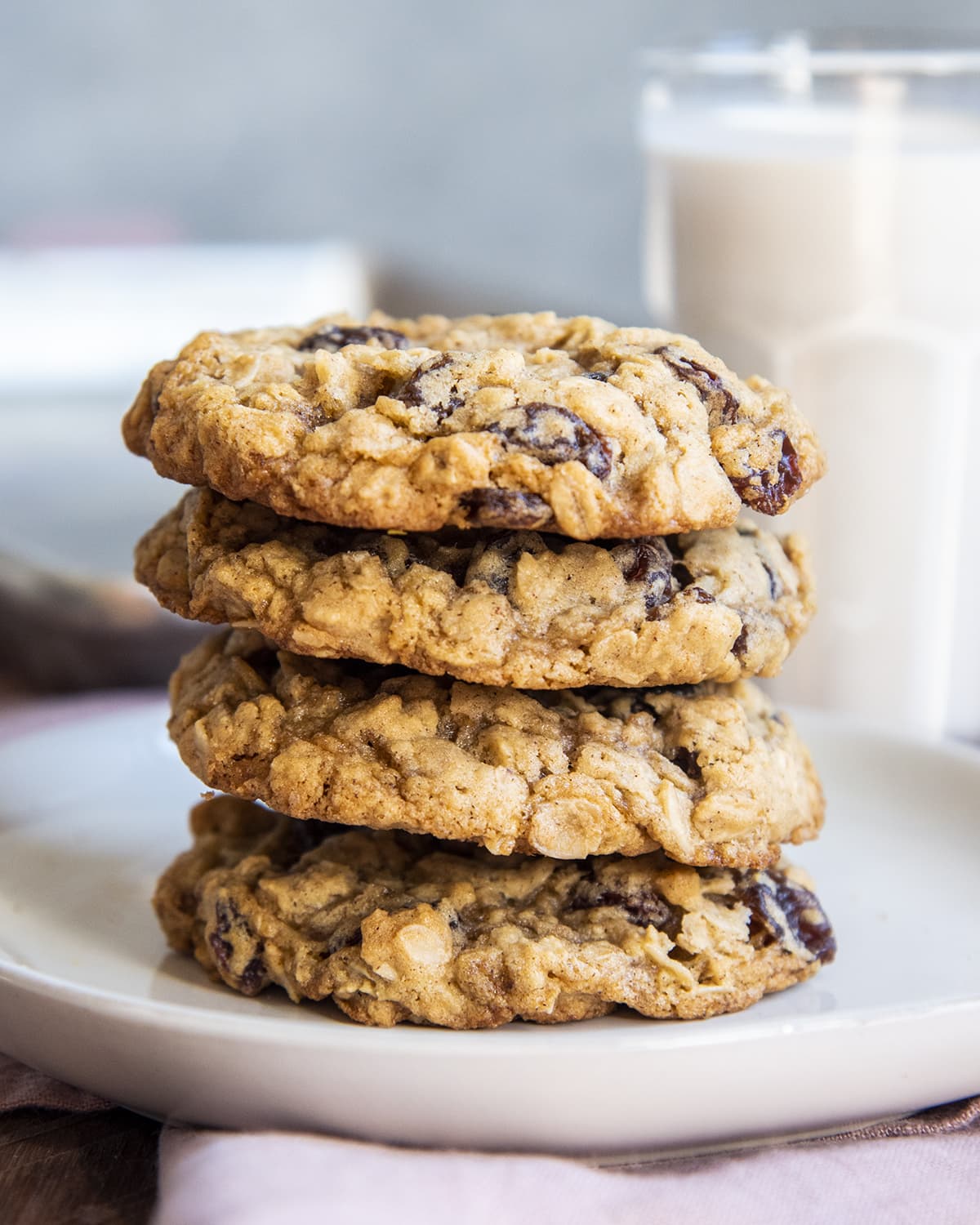 A stack of 4 oatmeal raisin cookies on a plate.