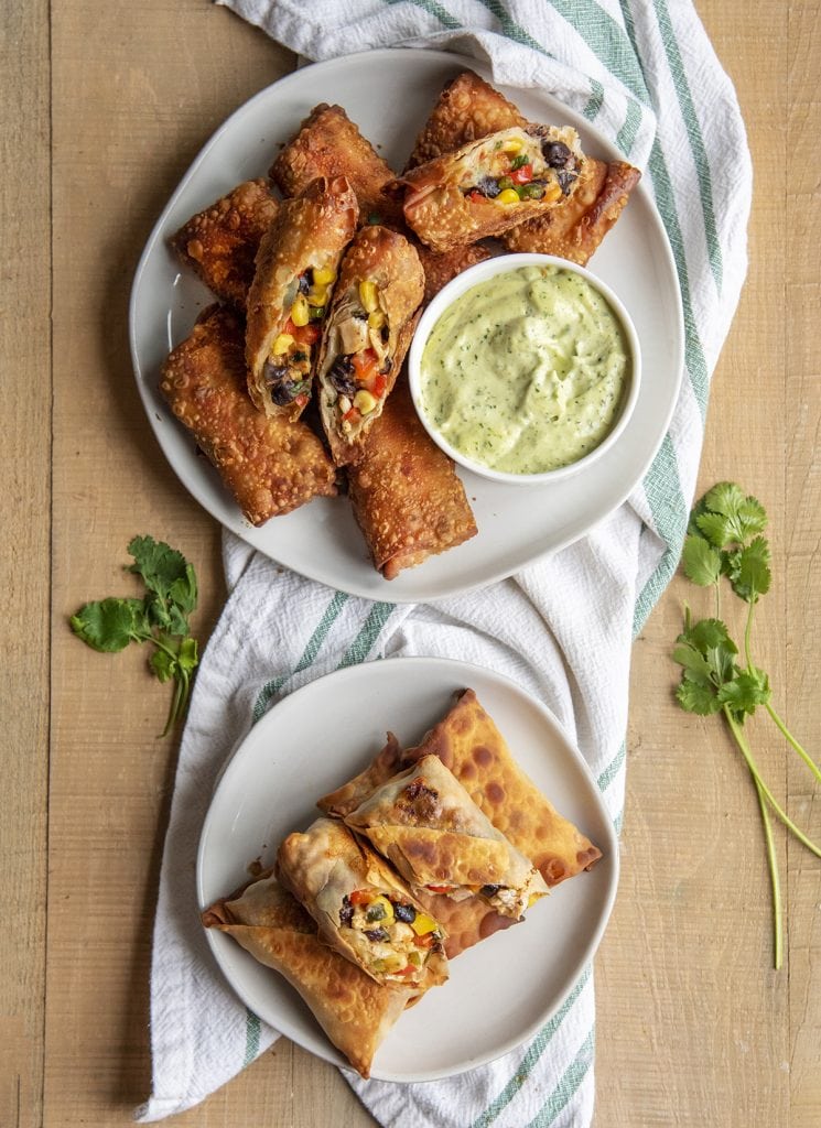 An overhead photo of two plates of southwest chicken egg rolls, one is fried, and one is baked.