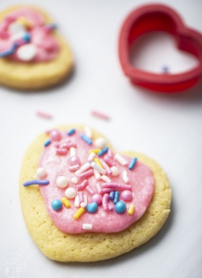 Sugar cookies for two close up image of single cookie with sprinkles and pink frosting.