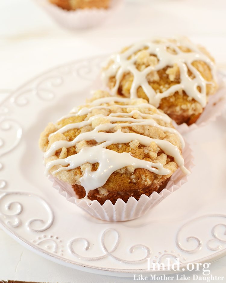 Two pumpkin muffins with icing on top on a white plate. 