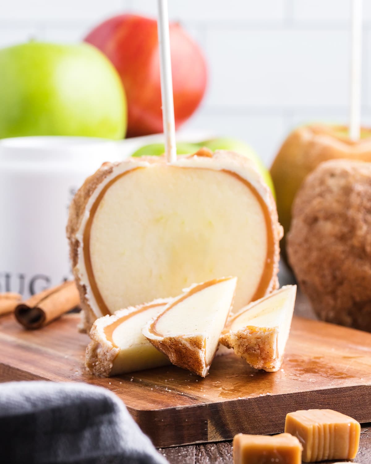 A cinnamon caramel apple cut up with three slices laying in front of it.