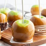 A caramel covered apple on a wooden board.