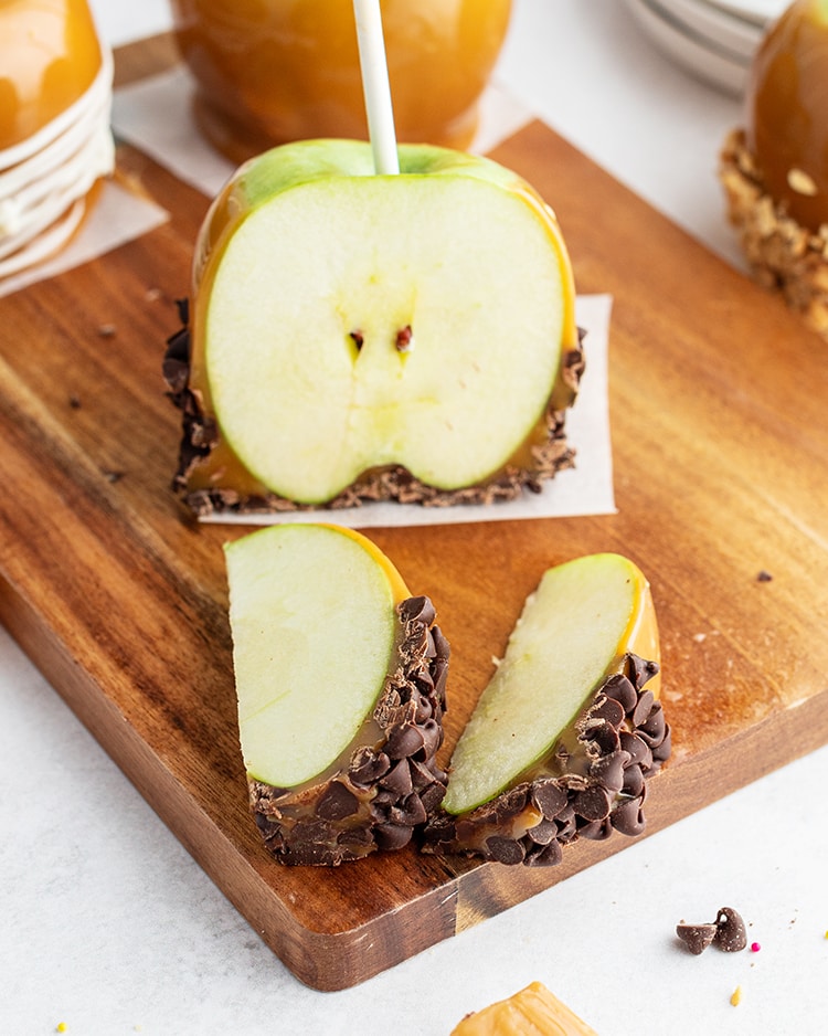 Slices of a caramel apple with chocolate chips on it.