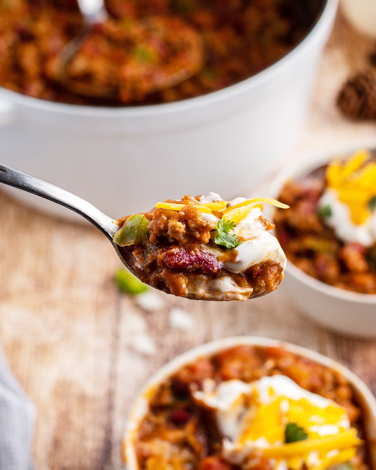A spoonful of chili topped with cheese and cilantro.