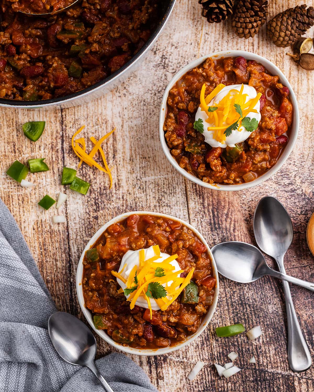 Two bowls of pumpkin chili topped with sour cream, cheese, and cilantro.