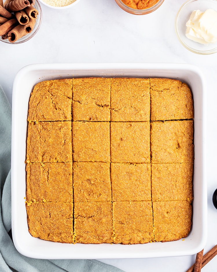 Pumpkin cornbread cut into pieces in a white baking dish
