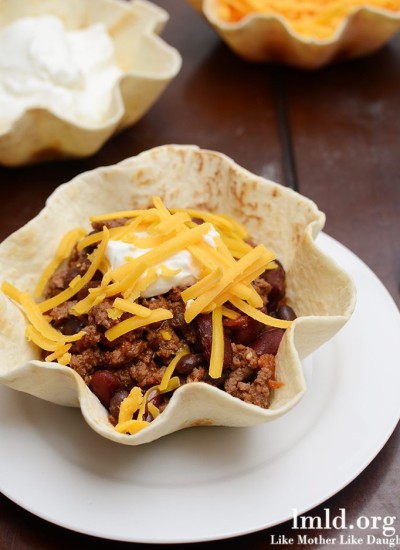 Top view of chili in tortilla bowls on a white plate.
