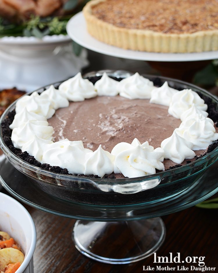 Front view of a chocolate pie in a glass pie pan with whipped cream.