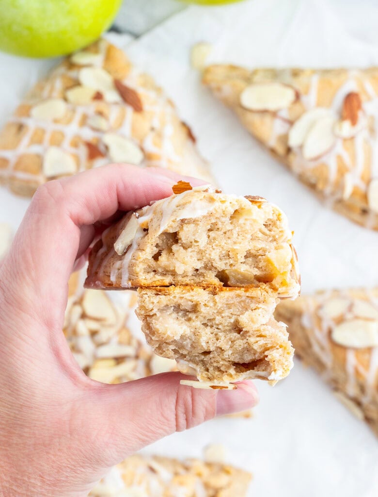 A hand holding two halves of an apple scone, showing the tender middle of the scone.