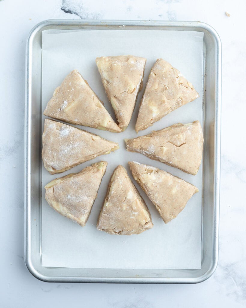 Unbaked triangle scones on a baking pan.