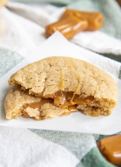 A caramel apple cider cookie broken in half and stacked on top of itself to show the caramel.