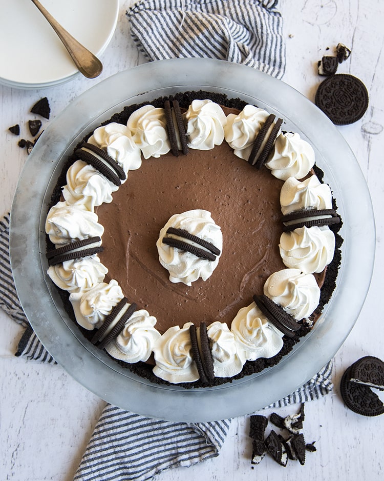 A chocolate cream pie in a pie pan topped with whipped cream and Oreos.