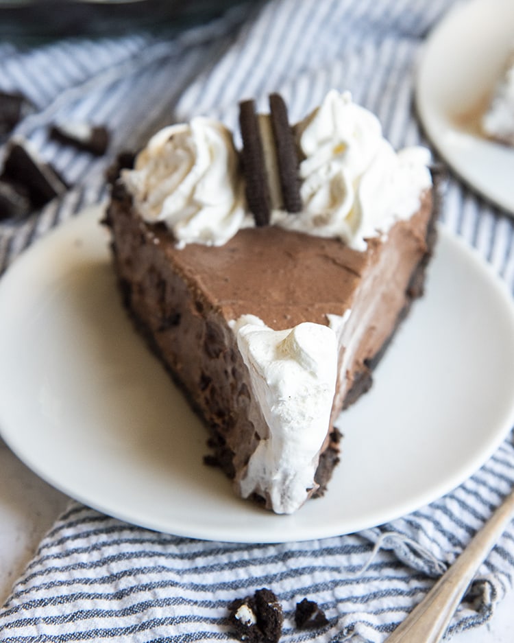 A piece of chocolate cream pie topped with whipped cream and a half oreo.