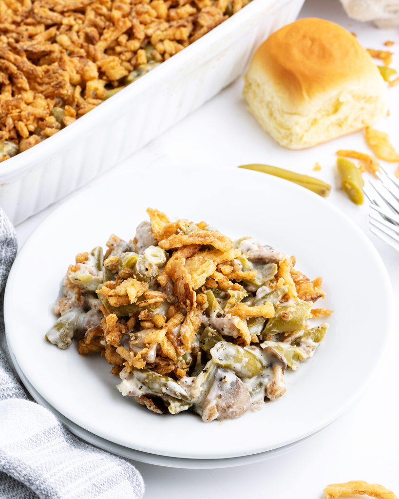 A plate of green bean casserole with green beans, mushrooms, and topped with crispy onion straws.