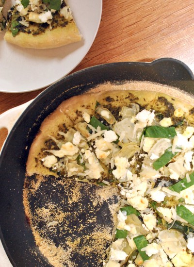 Top view of spinach artichoke pizza in a cast iron pan.