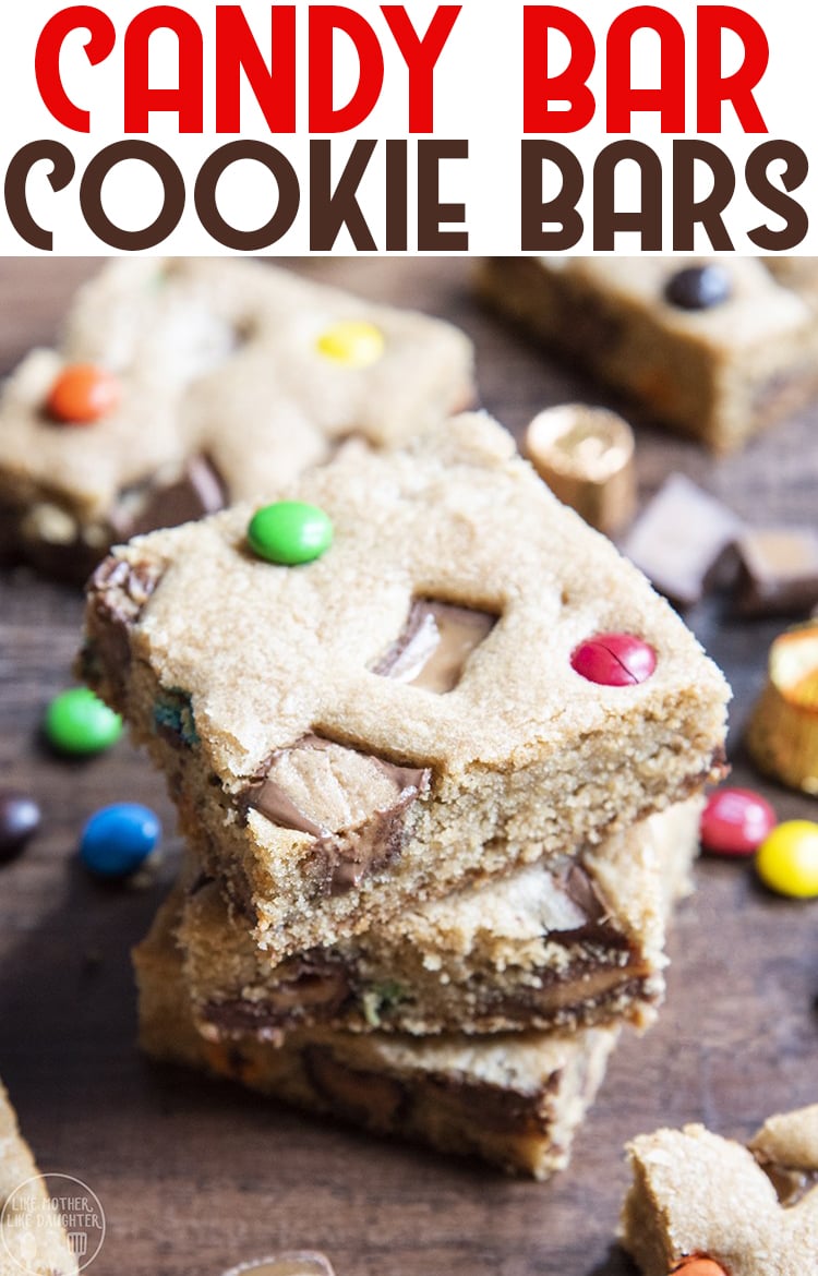 A stack of two cookie bars loaded with m&ms and candy bar pieces. 