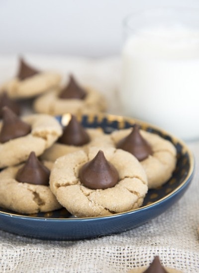 A plate of peanut butter blossom cookies with hershey kisses on them.