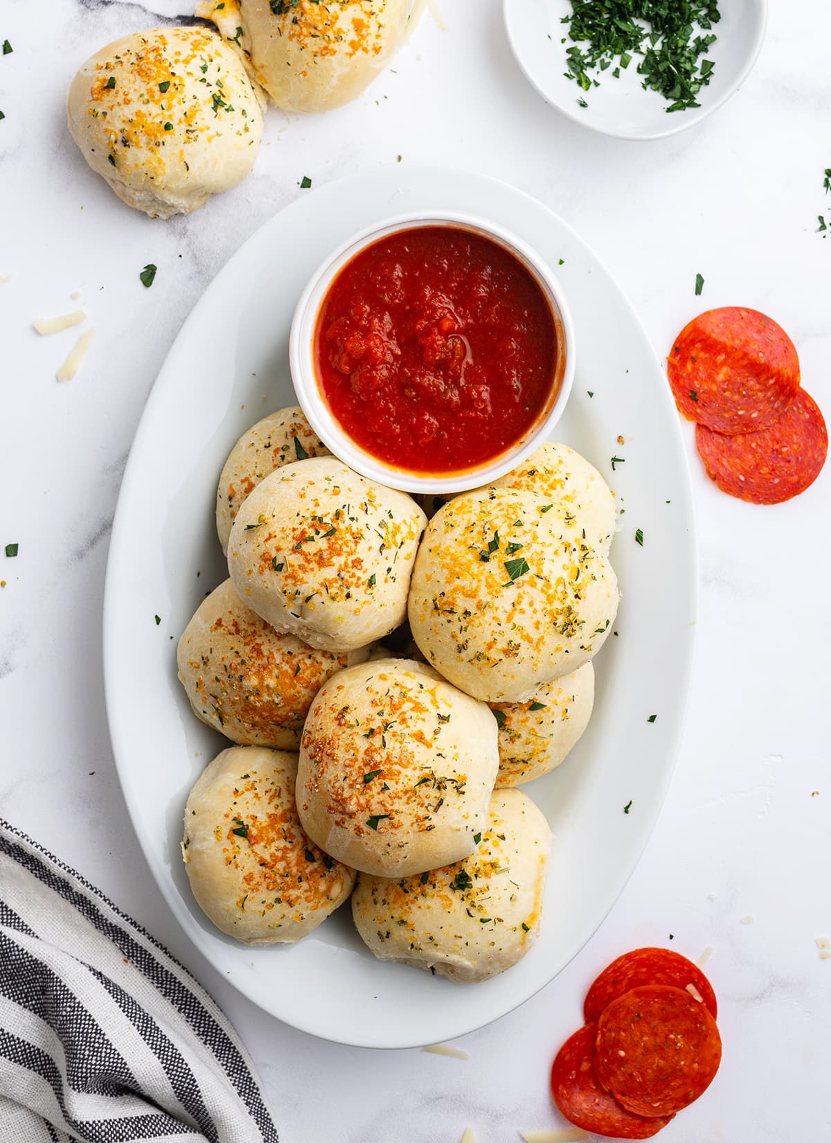 An overhead photo of a plate of pizza stuffed rolls on a plate next to a bowl of marinara sauce.