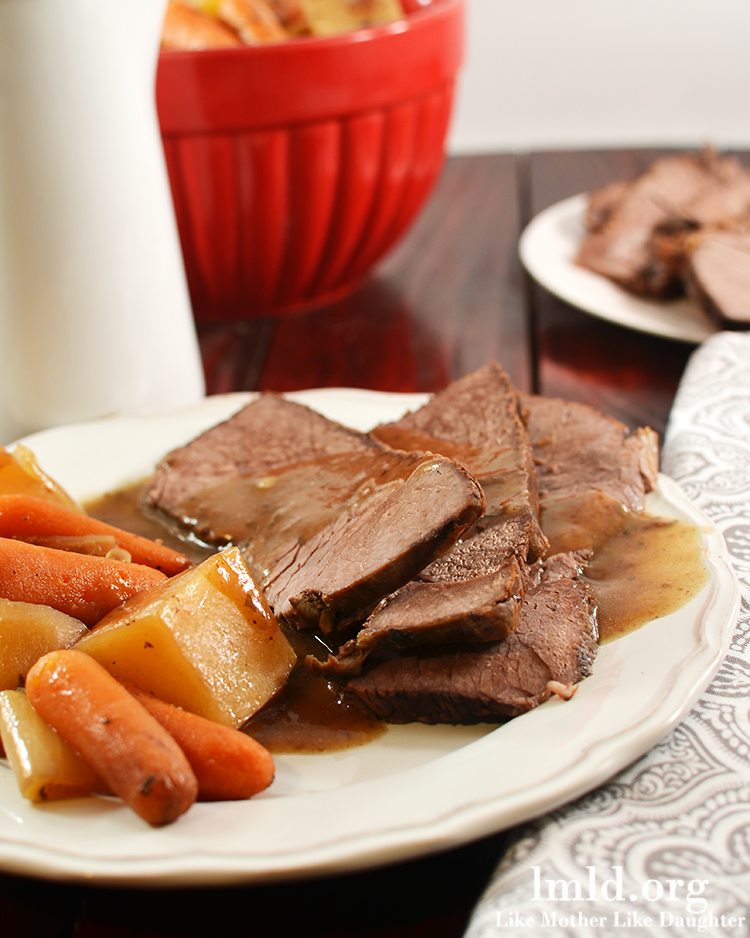 Angled view of tavern style crock pot beef roast on a white plate.