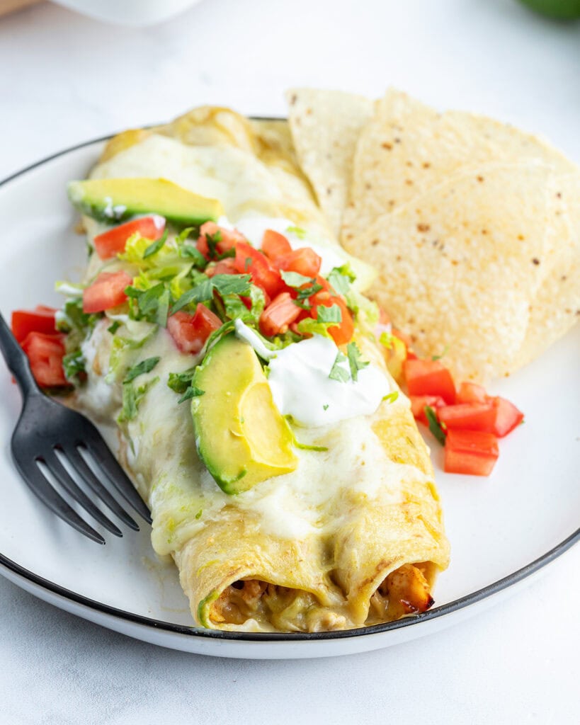 A plate of chicken enchiladas and tortilla chips.