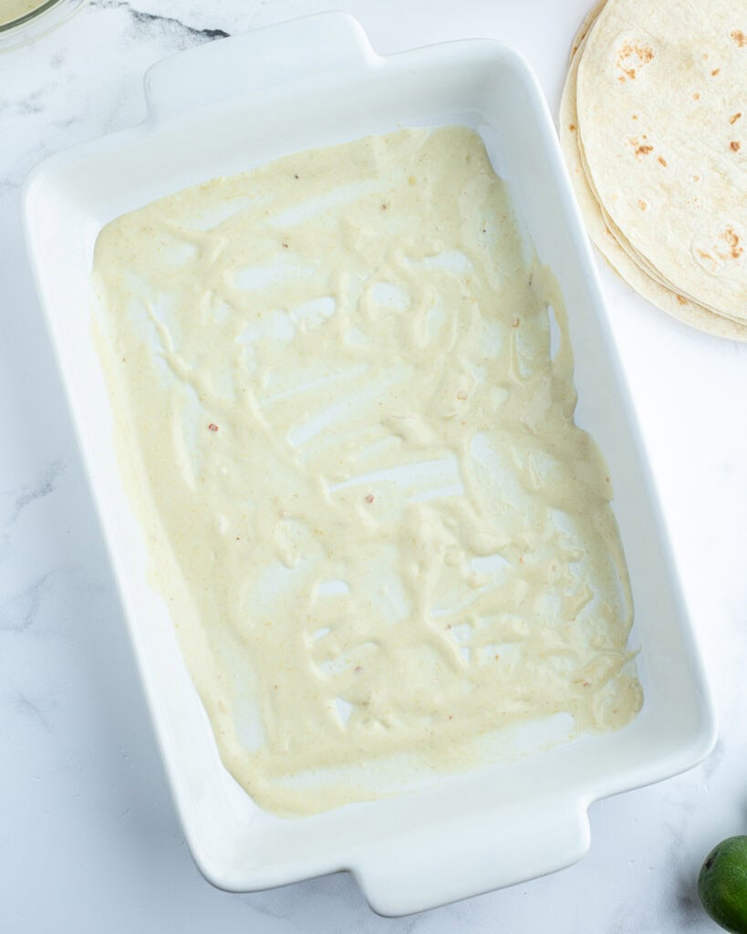 A pan with a creamy enchilada sauce in the bottom.