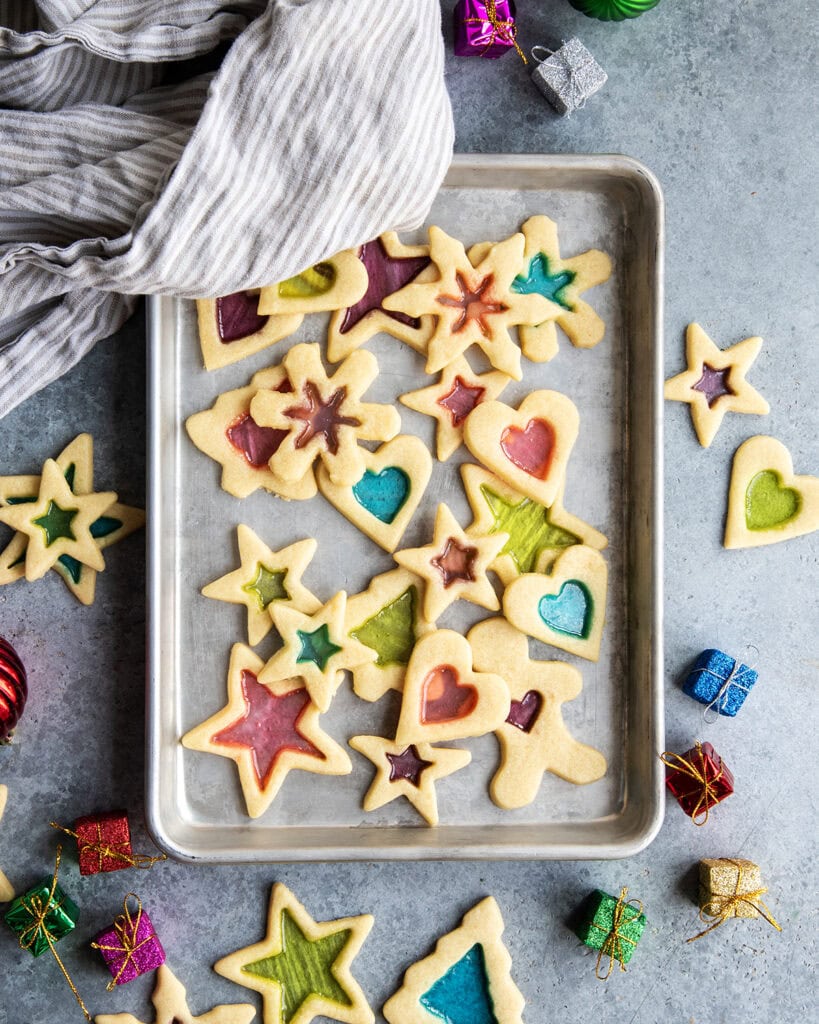 An above view of a cookie sheet loaded with stained glass window sugar cookies, with colorful candy centers.
