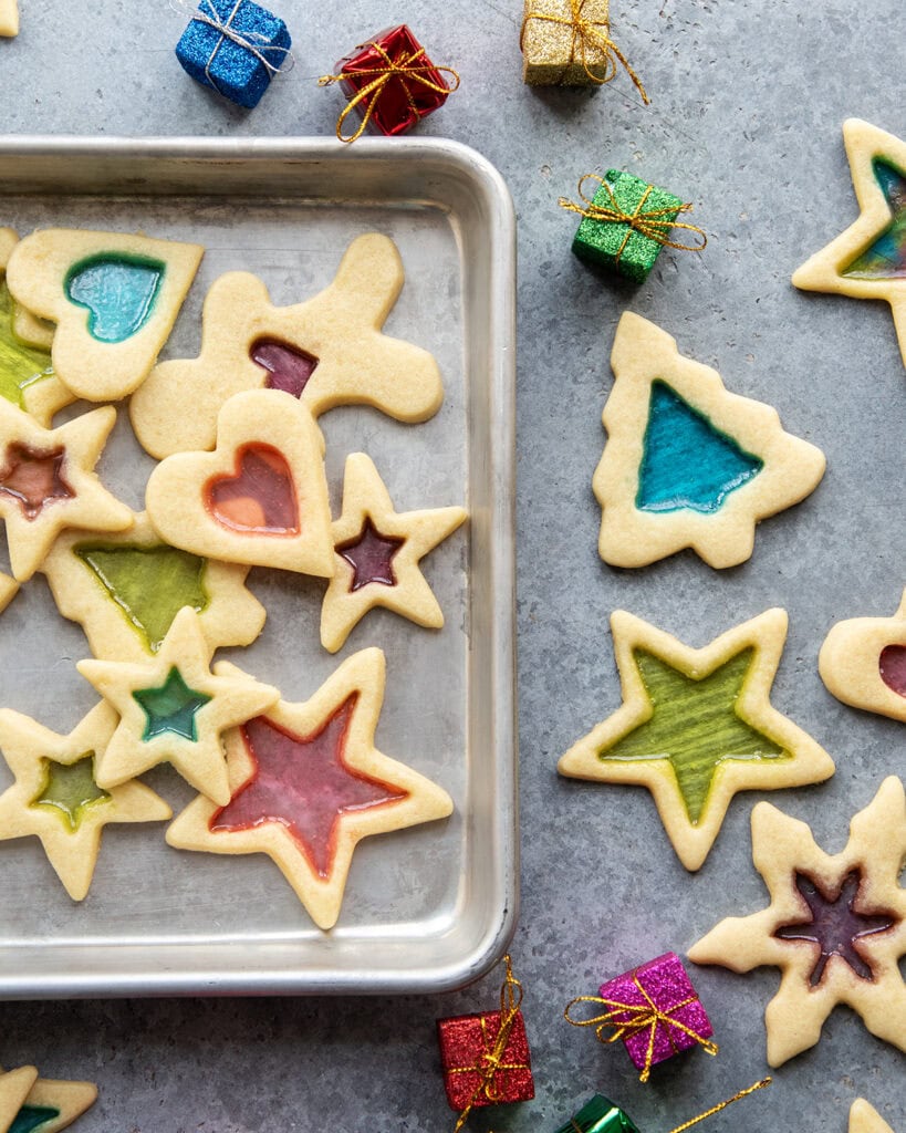 An above view of a cookie sheet loaded with stained glass window sugar cookies, with colorful candy centers.