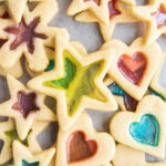 A pile of stained glass window cookies with a green stained star on top.