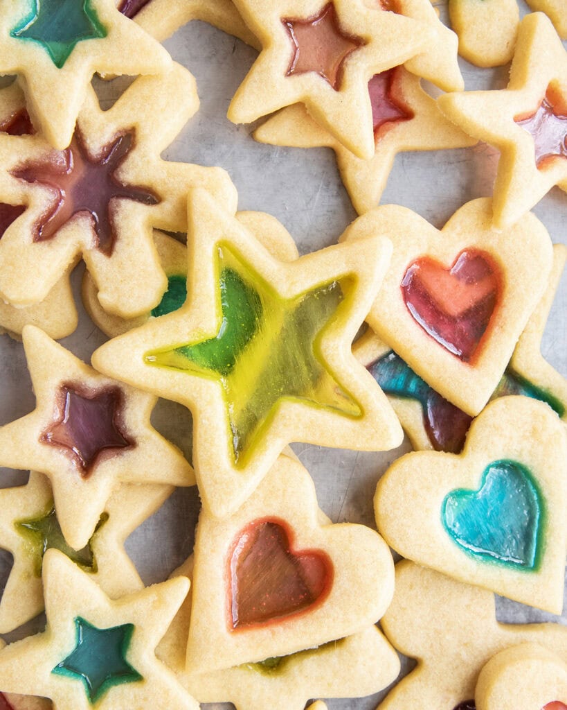 A pile of stained glass window cookies with a green stained star on top.