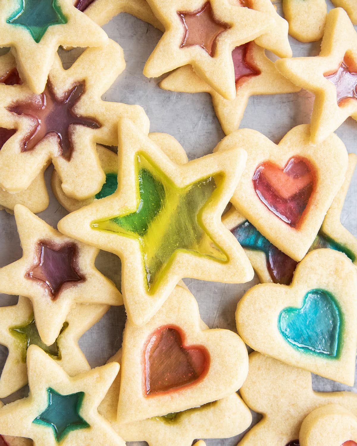 A pile of stained glass window cookies with a green stained star on top.