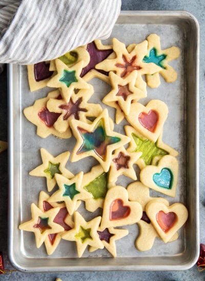 An above view of a cookie sheet loaded with stained glass window sugar cookies, with colorful candy centers.
