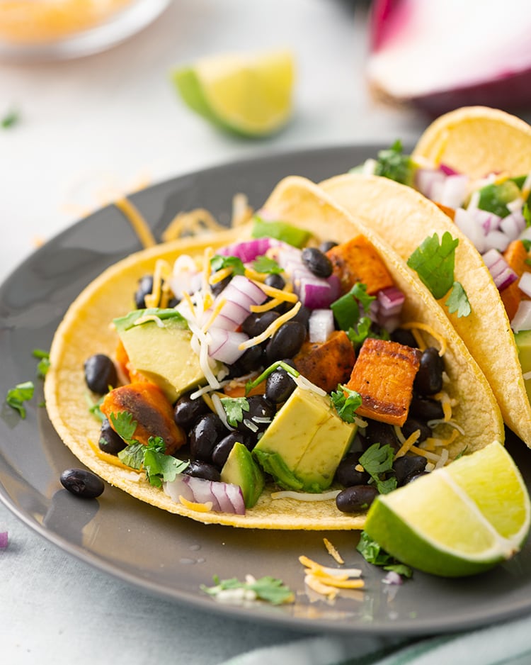 Sweet Potato and Black Bean Tacos topped with avocado, cheese, and lime juice.