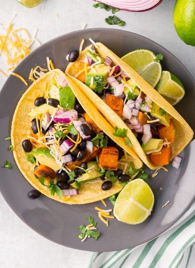 Two corn tortillas filled with sweet potatoes, black beans, red onion, avocado and cilantro.