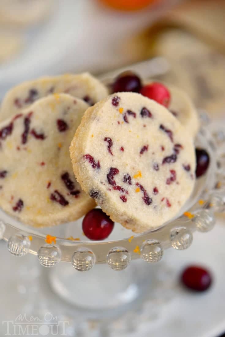 Angled view of cranberry orange shortbread cookies on a glass bowl.