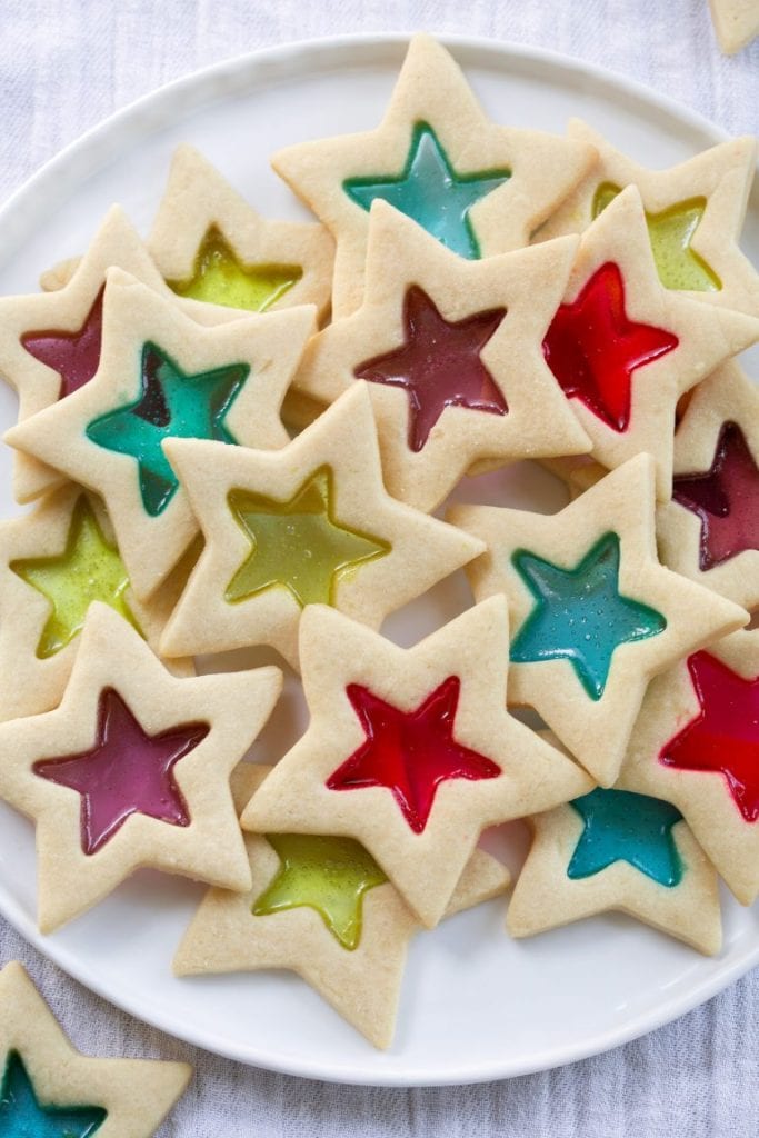 A plate of star shaped stained glass window cookies filled with red, green, blue and purple.