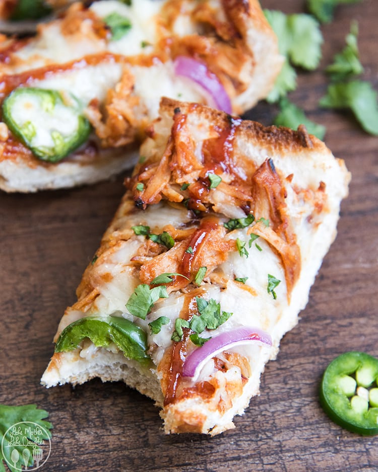 A slice of bbq chicken french bread pizza sitting on top of a wooden cutting board.