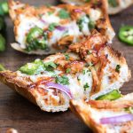 Slices of bbq chicken french bread pizza topped with red onion, and jalapenos.