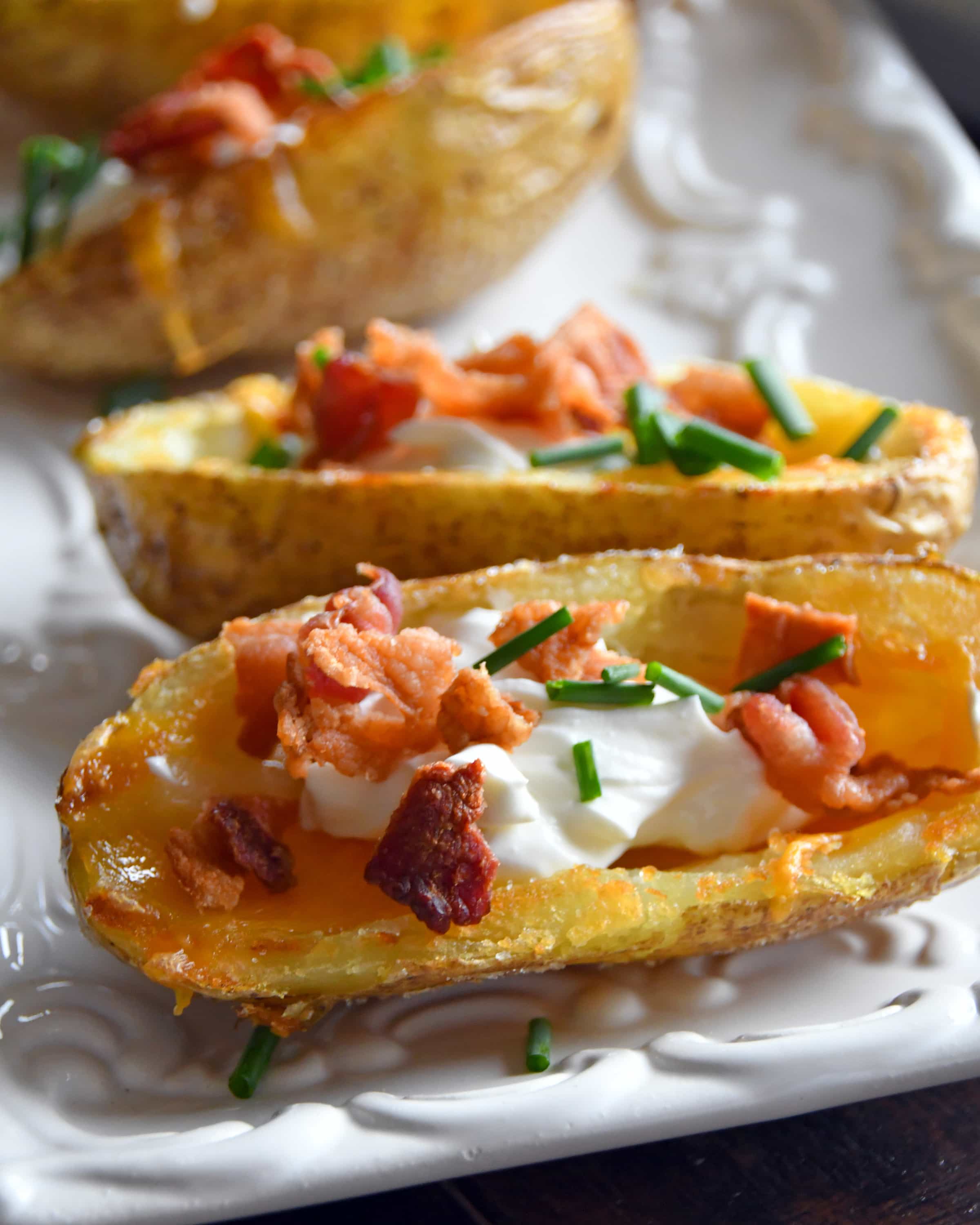 Front view of potato skins on a white plate with toppings.