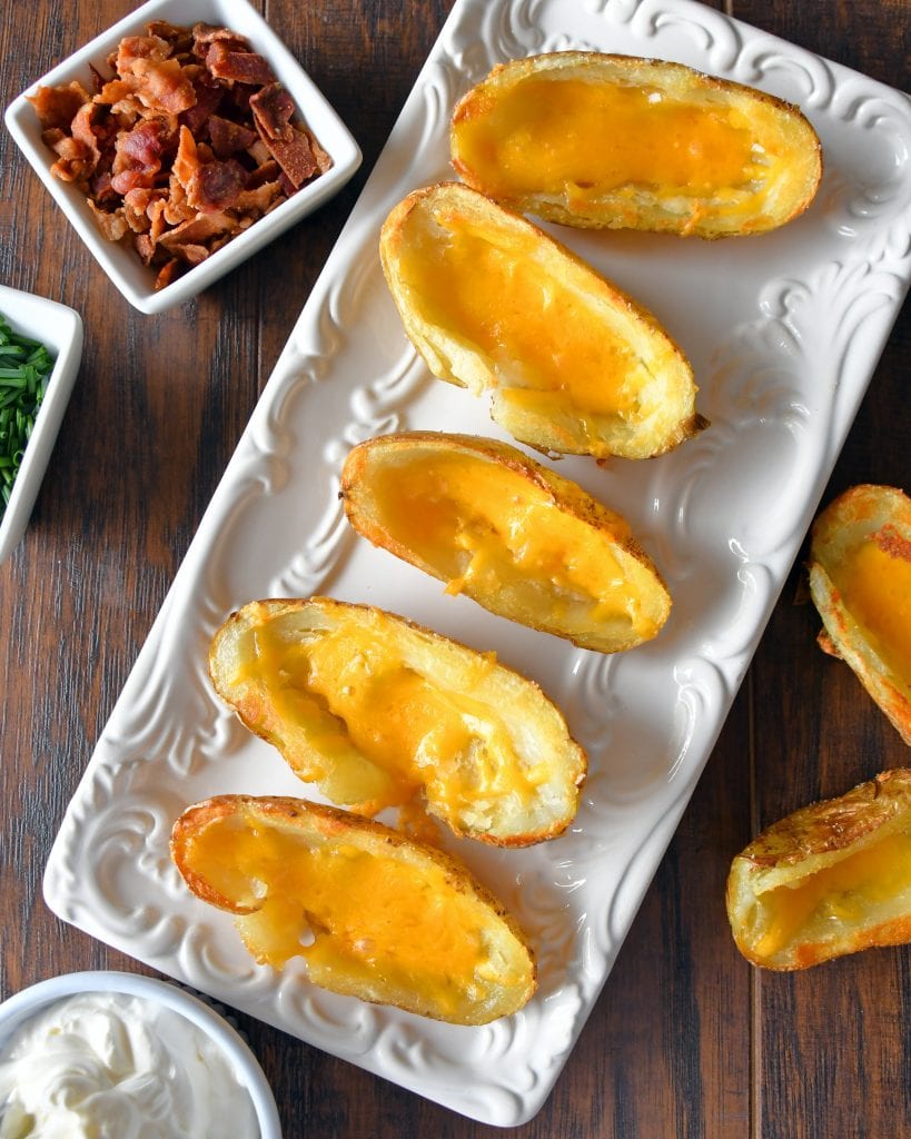 Top view of potato skins on a white plate with cheese.