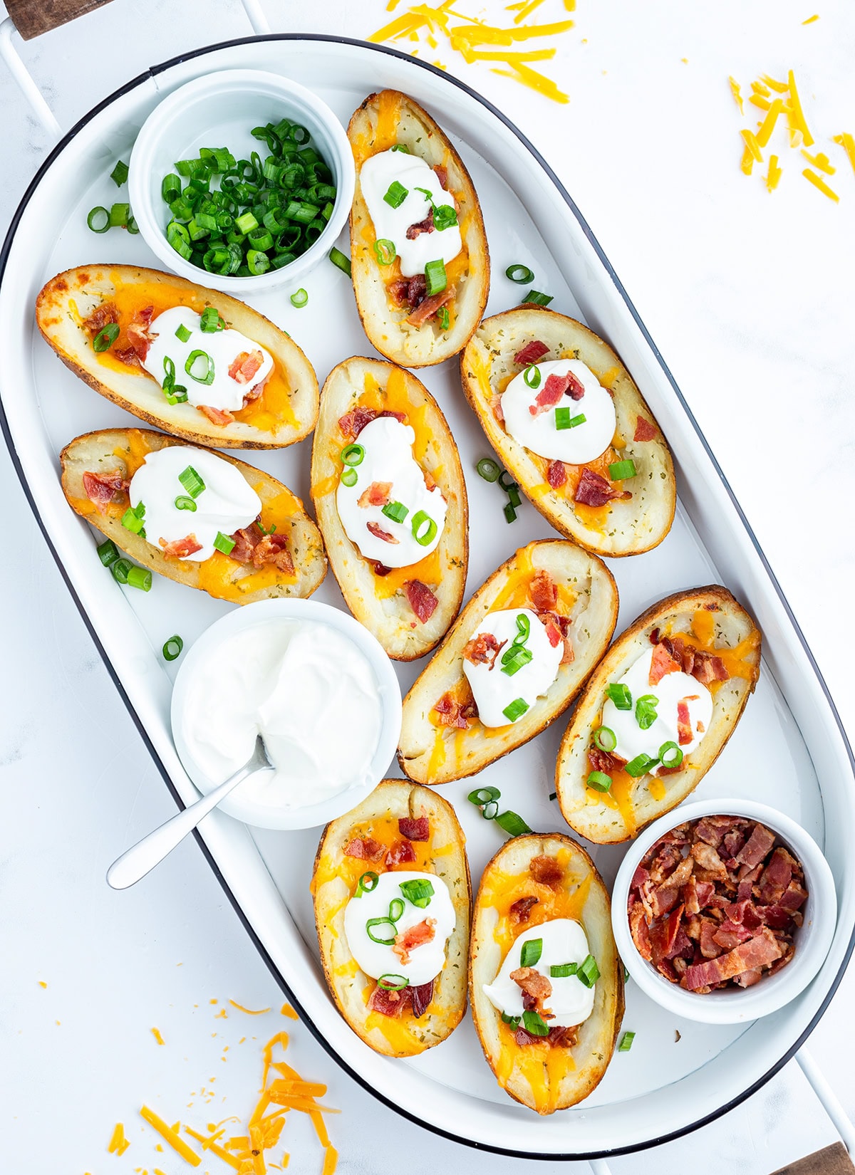 A tray of baked potato skins topped with cheese, sour cream, and bacon.