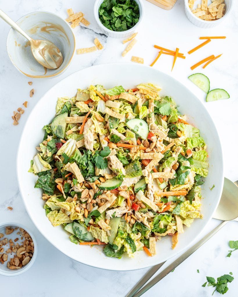 A bowl of Thai chicken salad with cucumbers, wonton strips, carrots, and shredded lettuce.