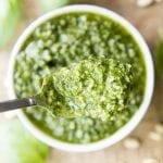 A spoonful of pesto above a small bowl of green pesto.