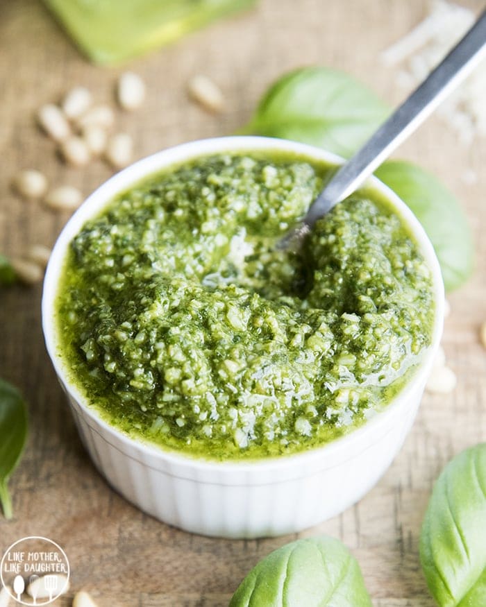 A small bowl of homemade pesto with a spoon in it.
