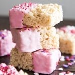 Side image of 3 pink rice krispie treats dipped in pink white chocolate and sprinkles.