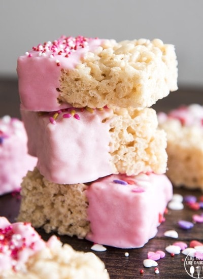 Side image of 3 pink rice krispie treats dipped in pink white chocolate and sprinkles.