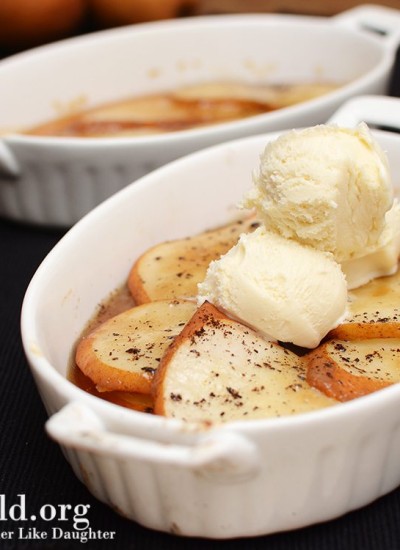 Angled view of caramelized pears with ice cream on top in a white bakeware.