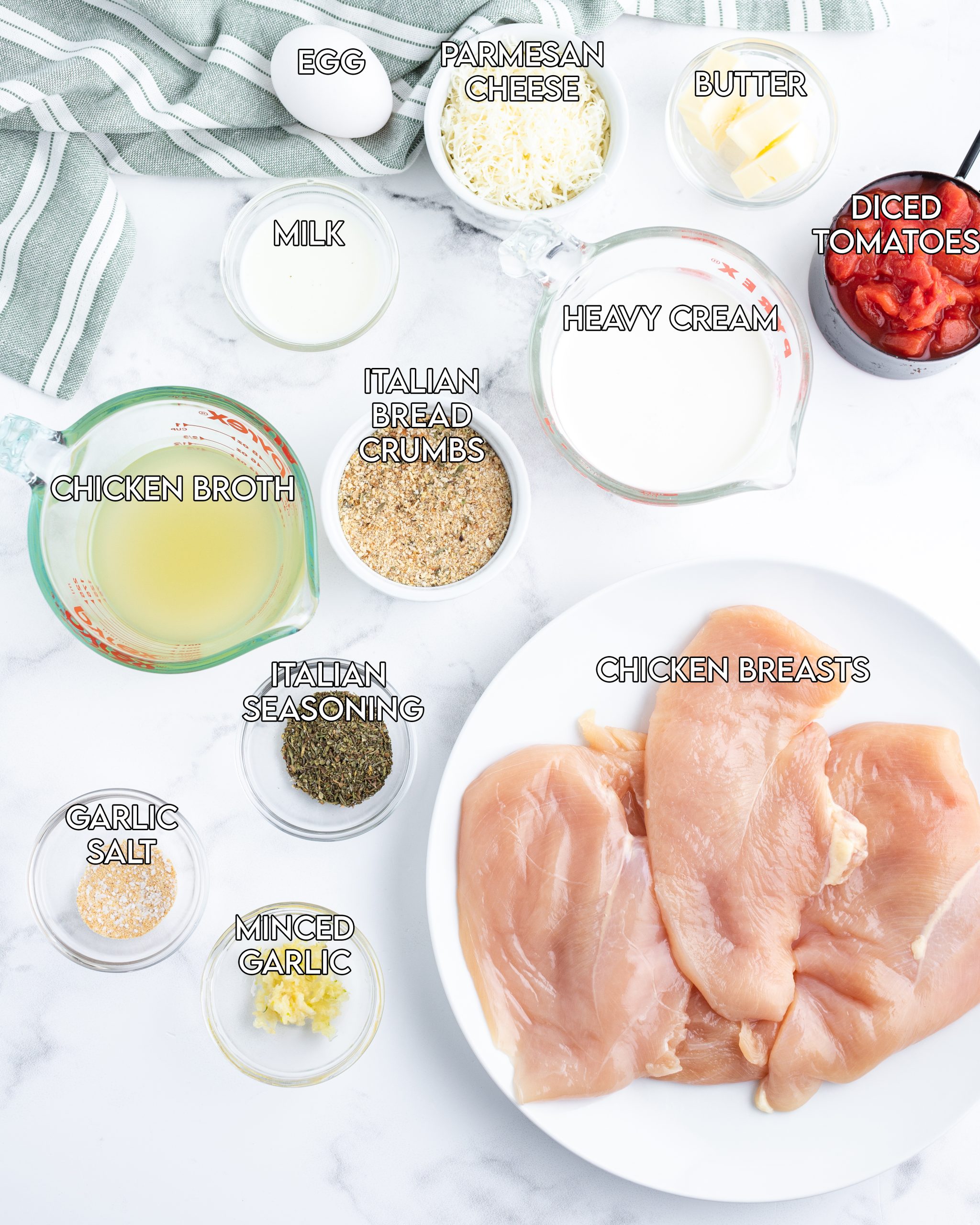 An overhead photo of the ingredients needed to make herb crusted chicken with tomato cream sauce. The ingredients are labeled with text, you've got chicken, chicken broth, heavy cream, diced tomatoes, italian seasonings, and more.