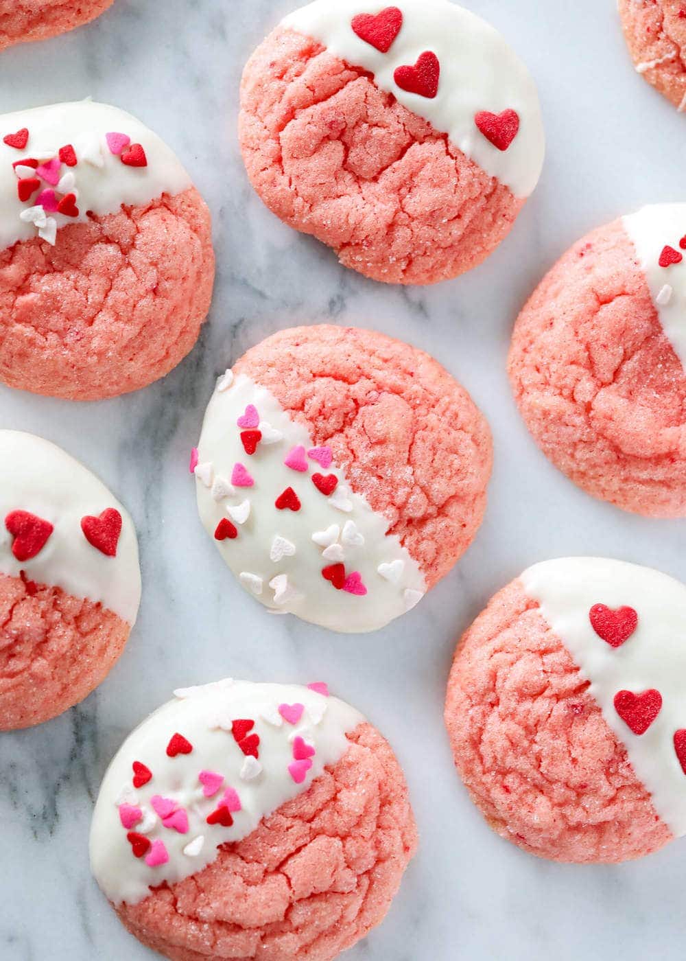 Above image of strawberry cookies half dipped in white chocolate and sprinkles.