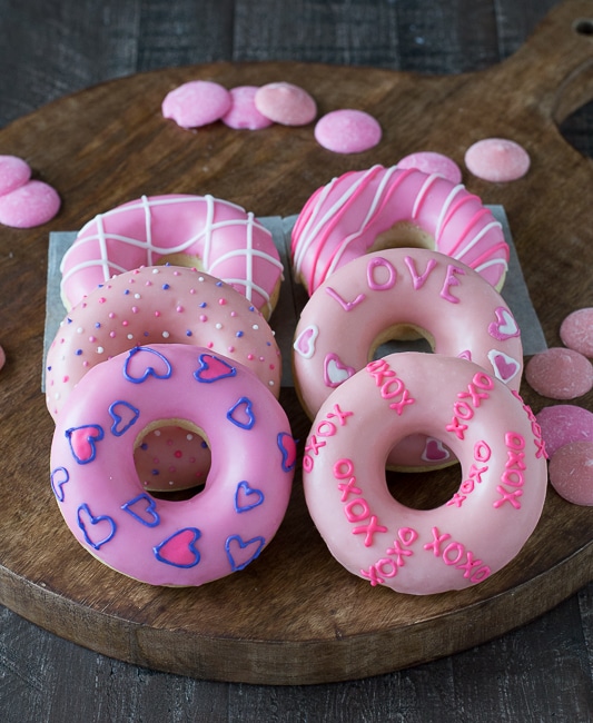 Above image of valentine\'s day donuts covered in pink frosting and other frosting decorations.